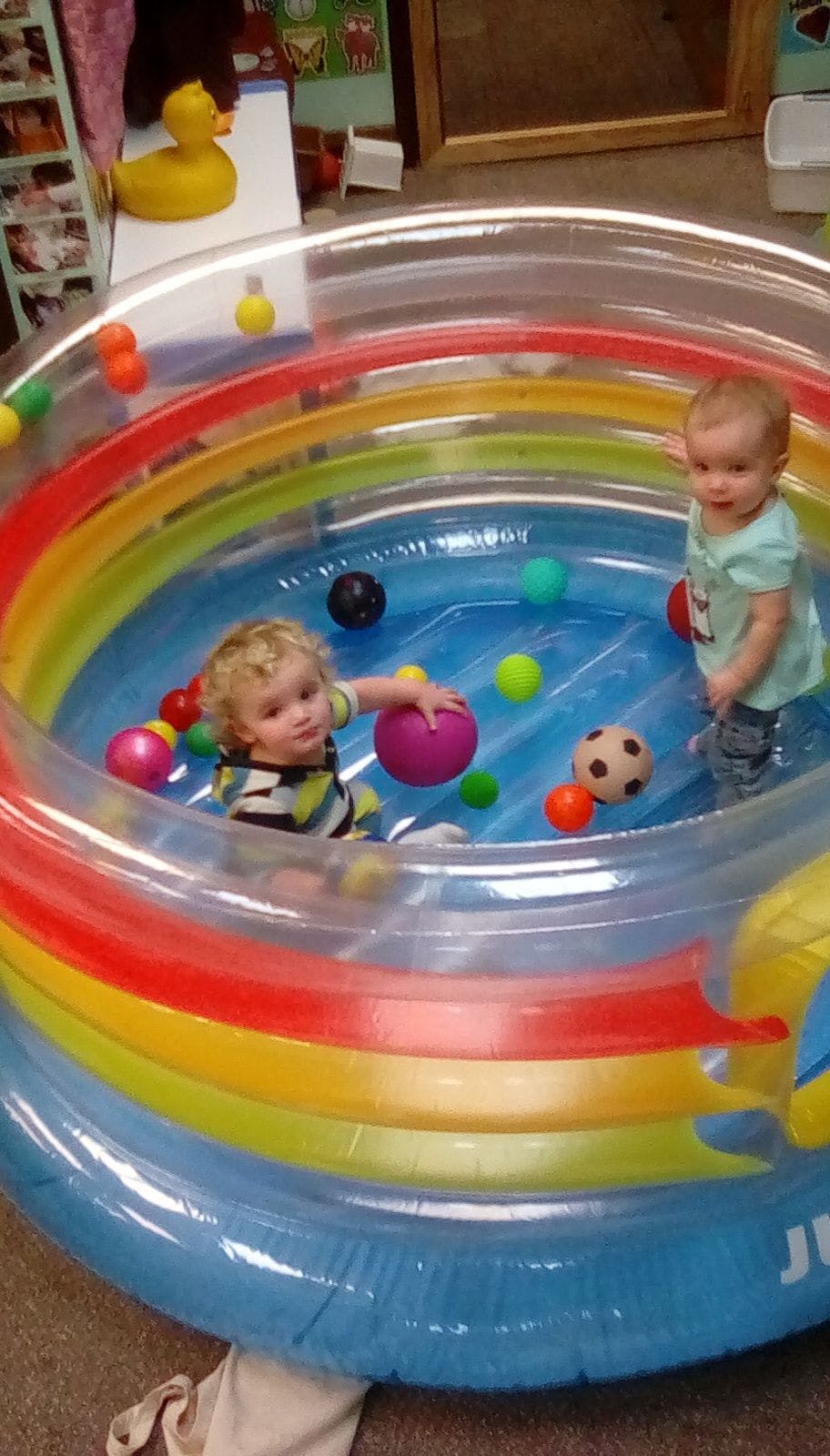 Two children playing with balls in an inflatable pool