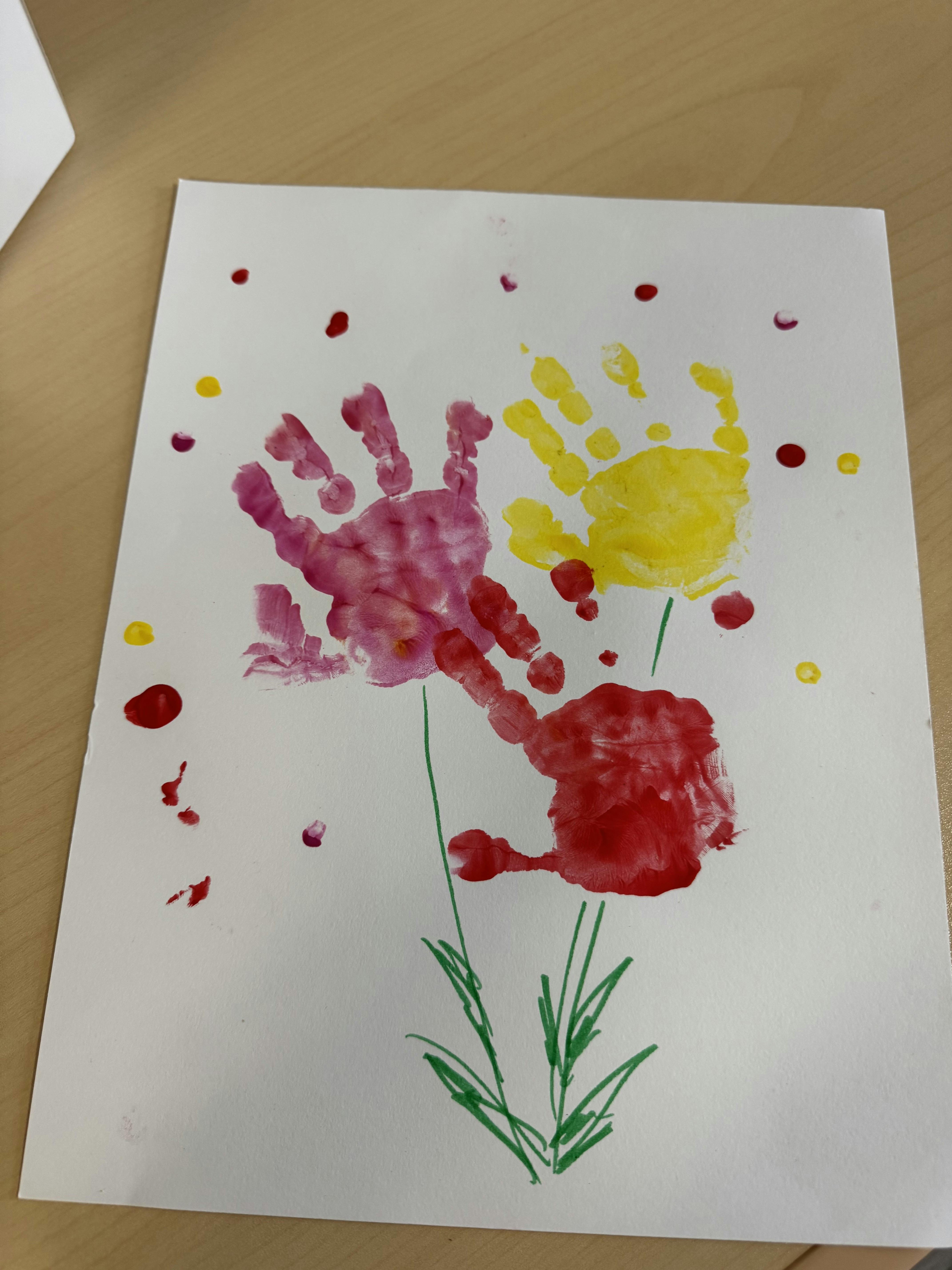 Child's art project using painted handprints as flowers on a white paper