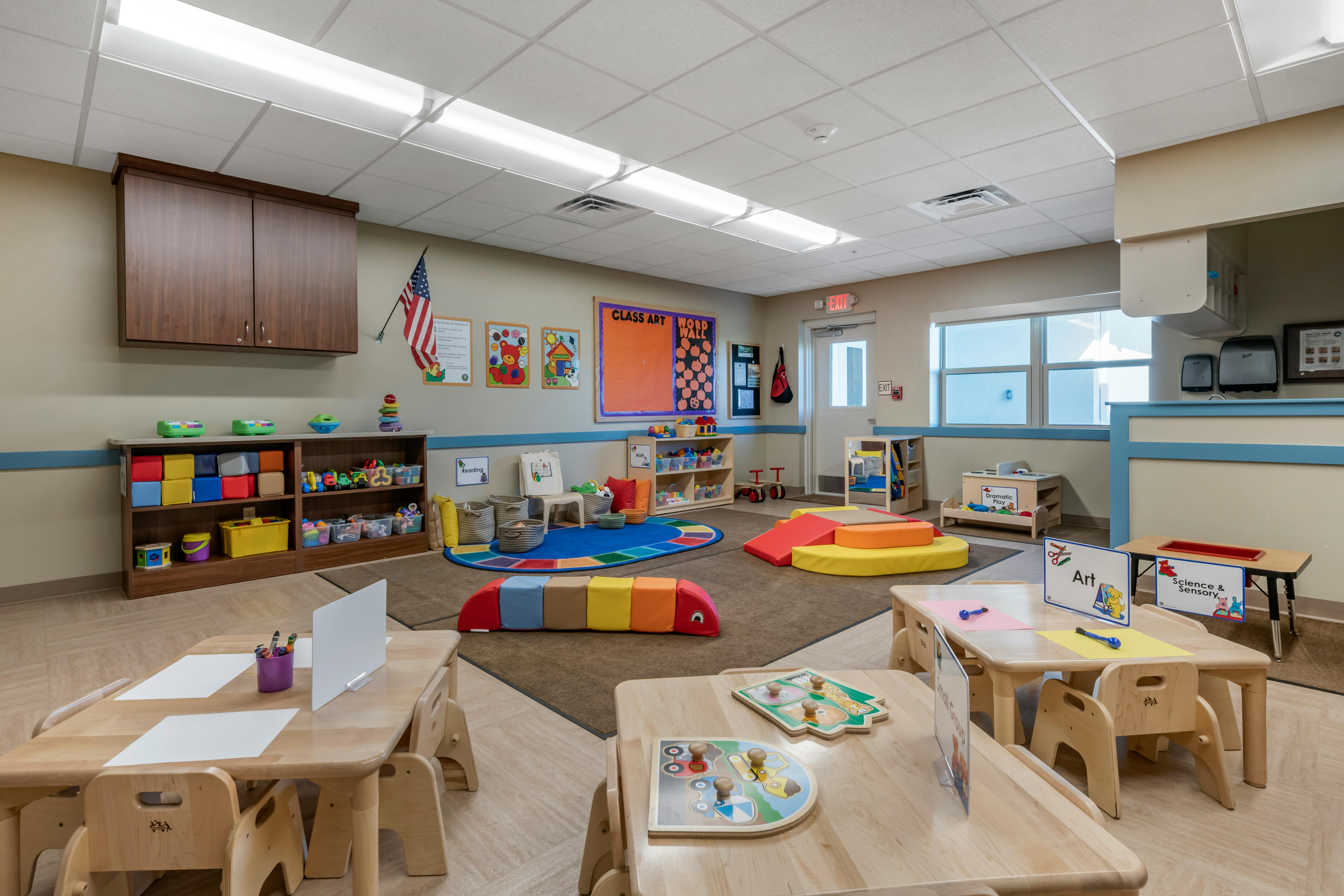 A colorful classroom with small tables and chairs, shelves of toys, and activity areas