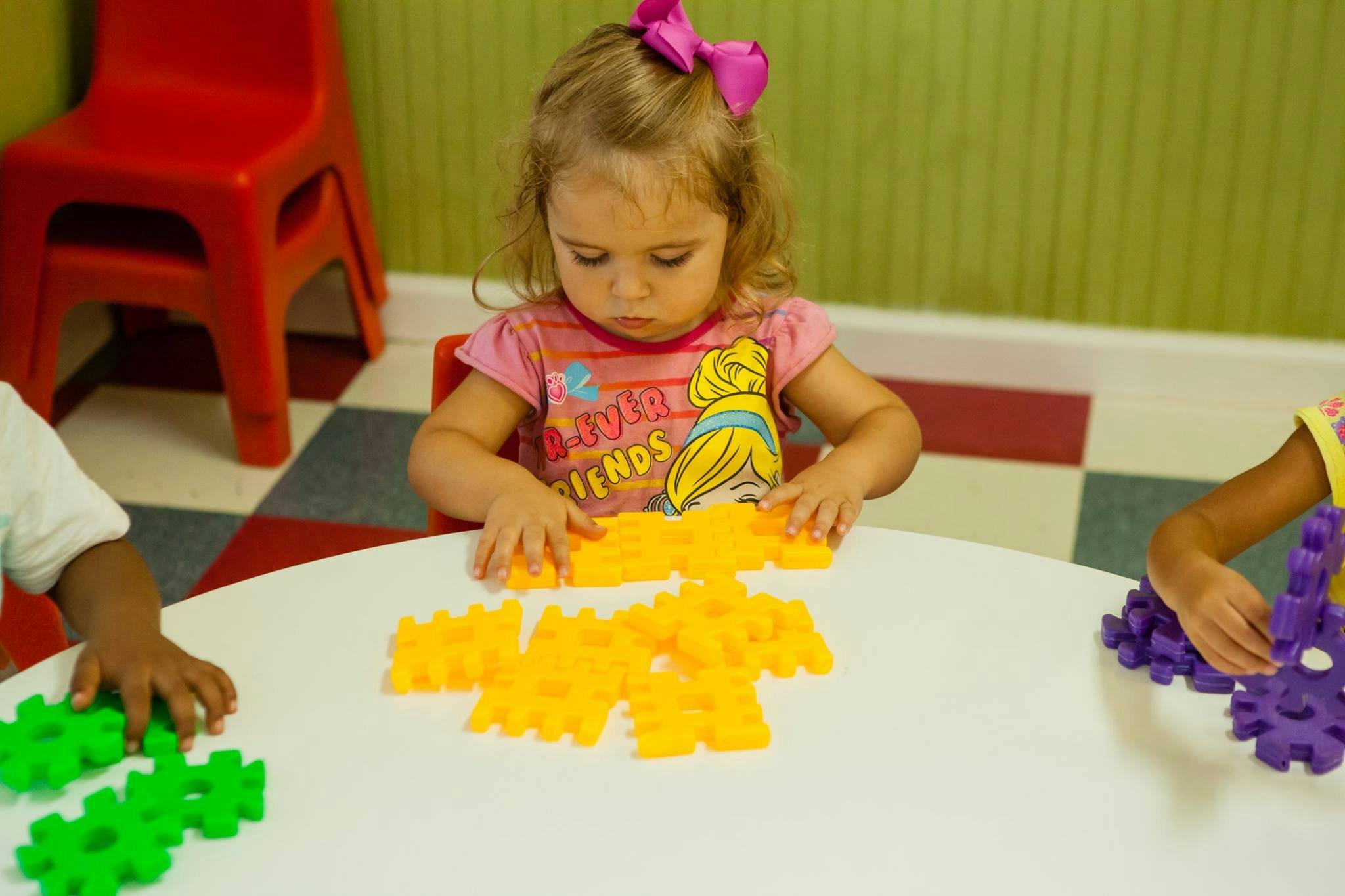 Child playing with yellow interlocking toys at a table