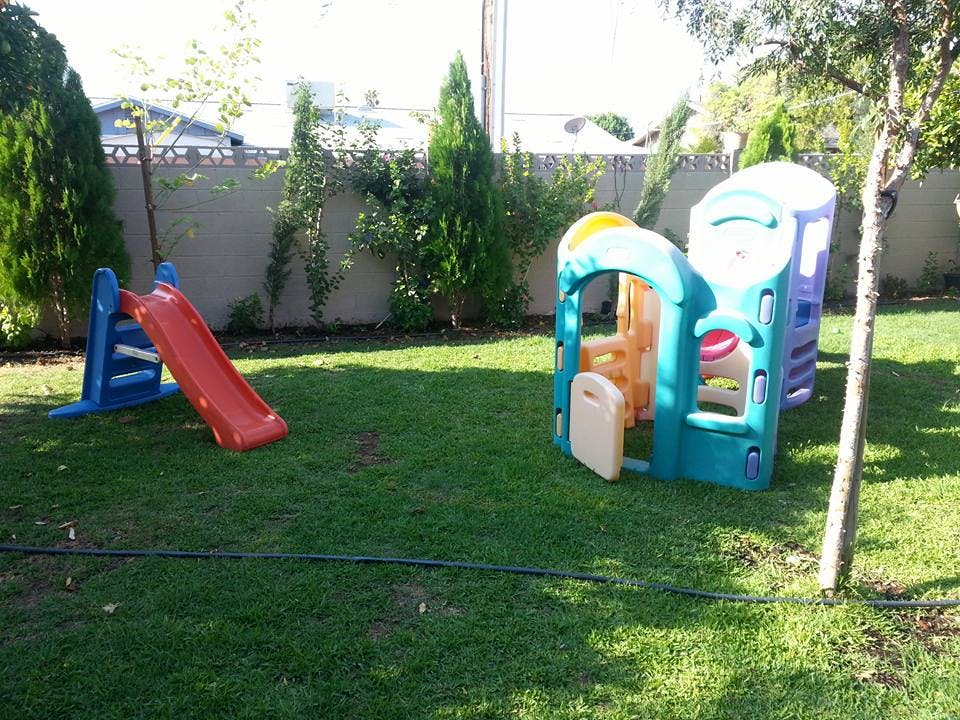 Red slide and playhouse on green grass
