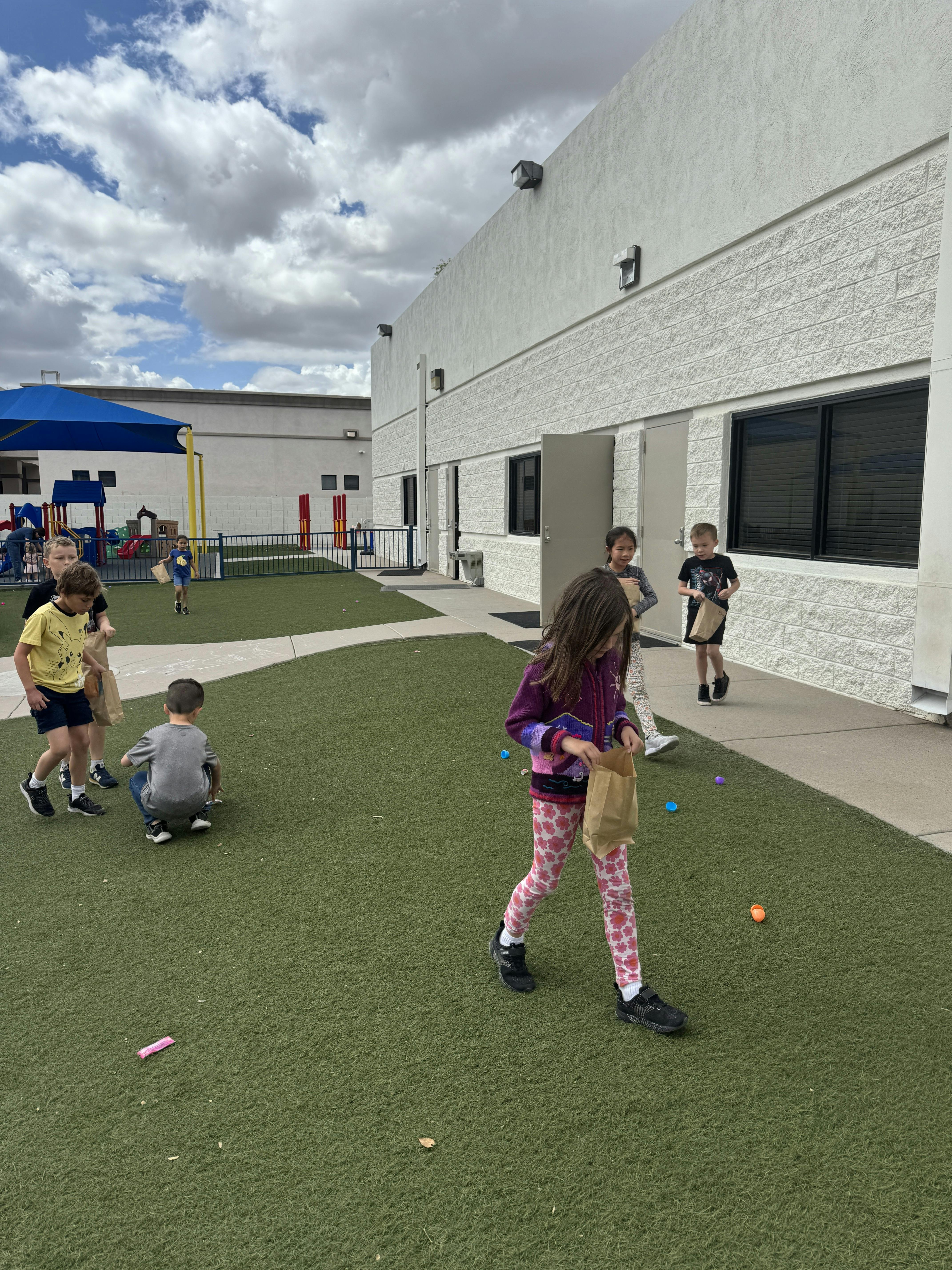 Children on a grassy area with a building in the background