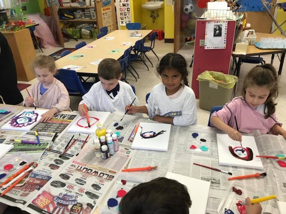 Children painting at a table in a classroom