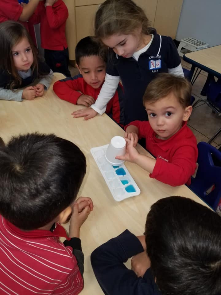 Children gathered around a table with an ice cube tray and cup