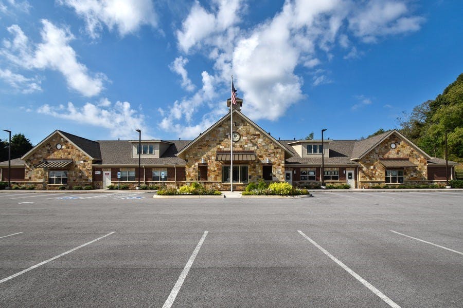 Stone building with a flagpole in front of a parking lot