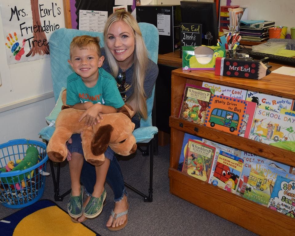 Person and child sitting in a chair, child holding a stuffed animal