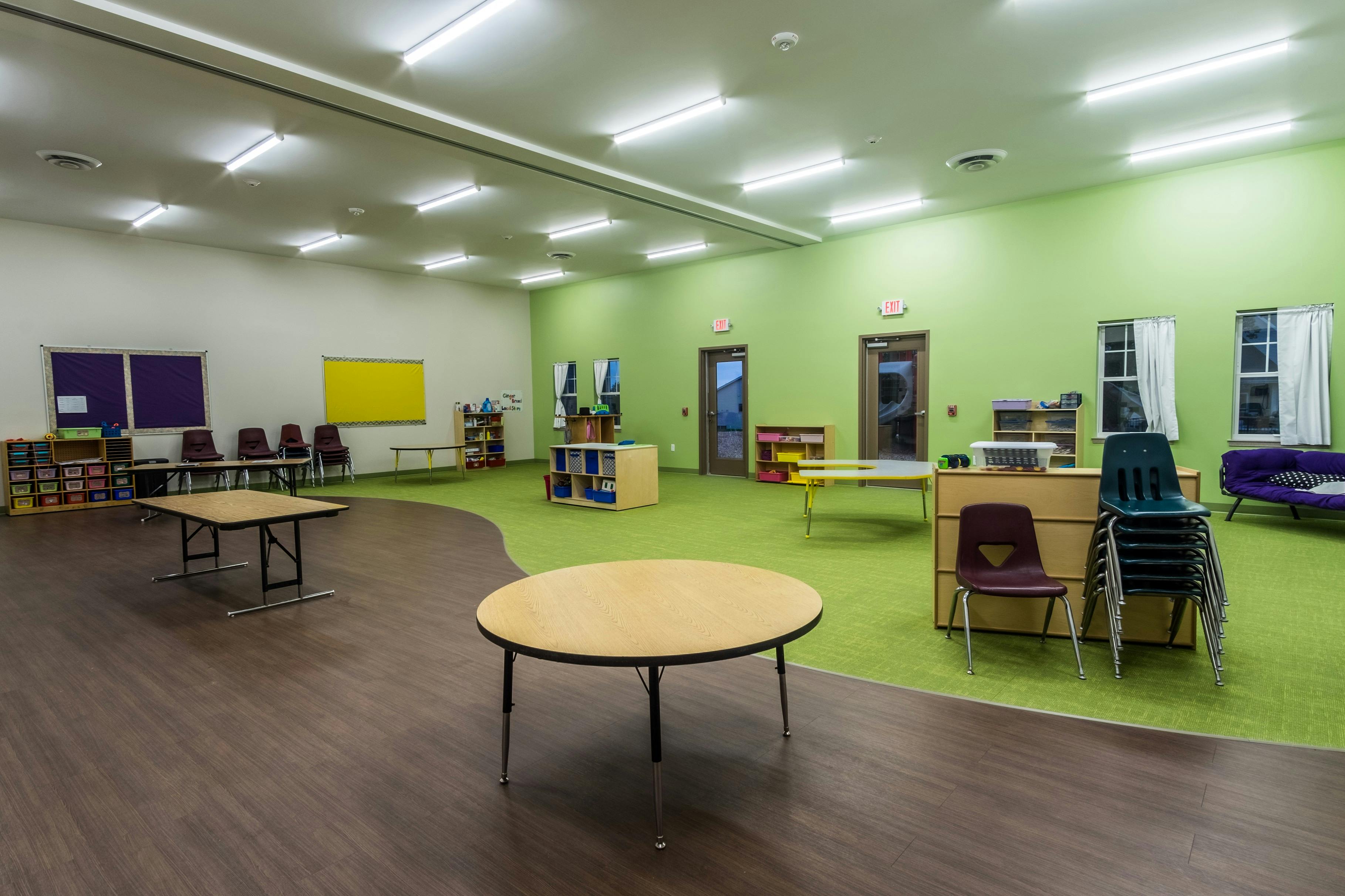 Empty classroom with green carpet and light wood tables