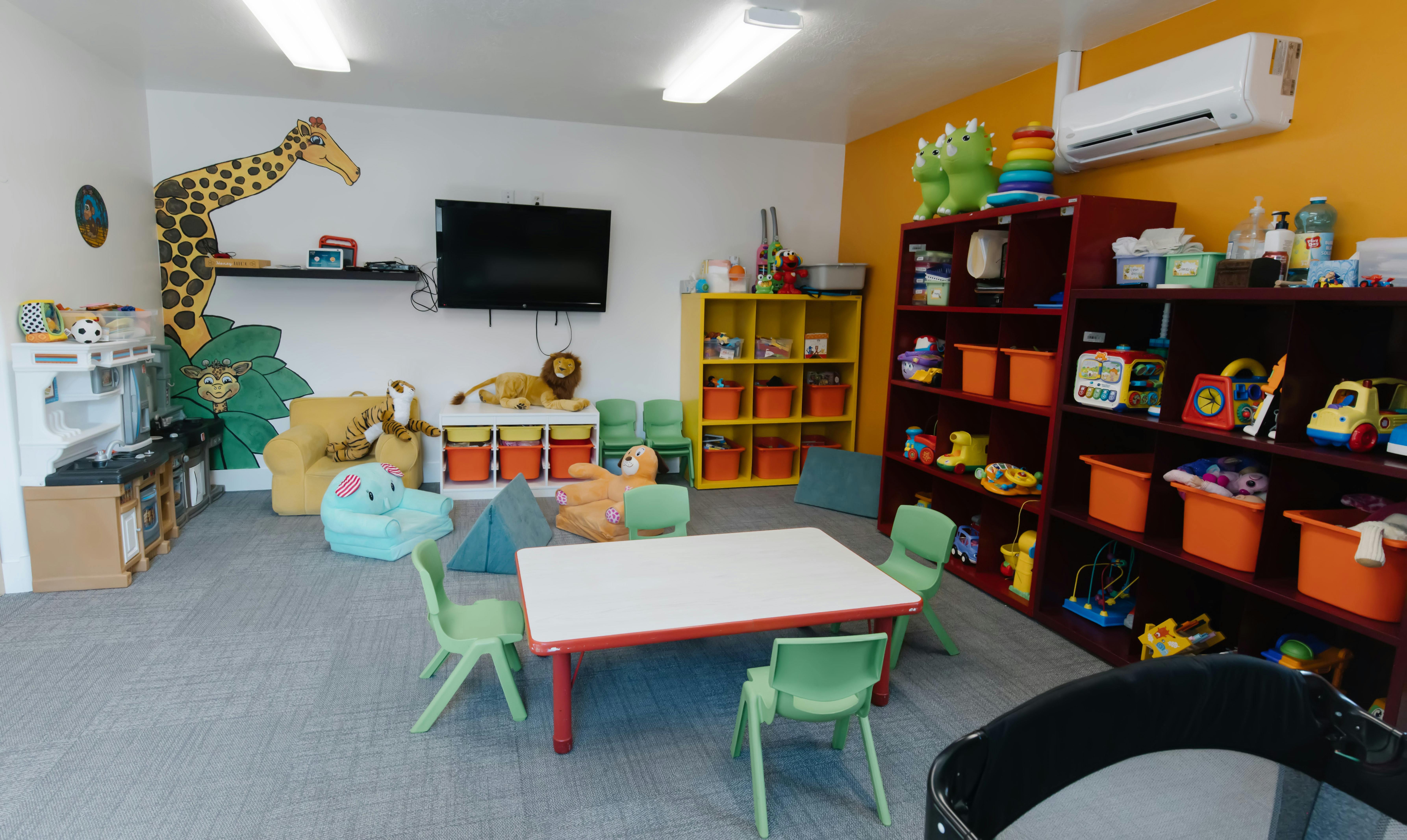 Playroom with small table and chairs, shelves of toys, and stuffed animals