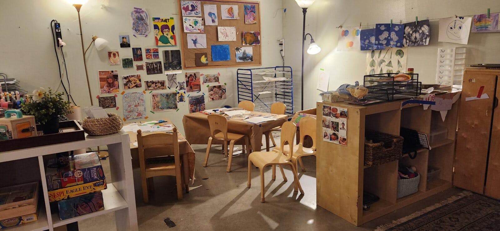 Children's art classroom with tables and chairs, artwork on walls