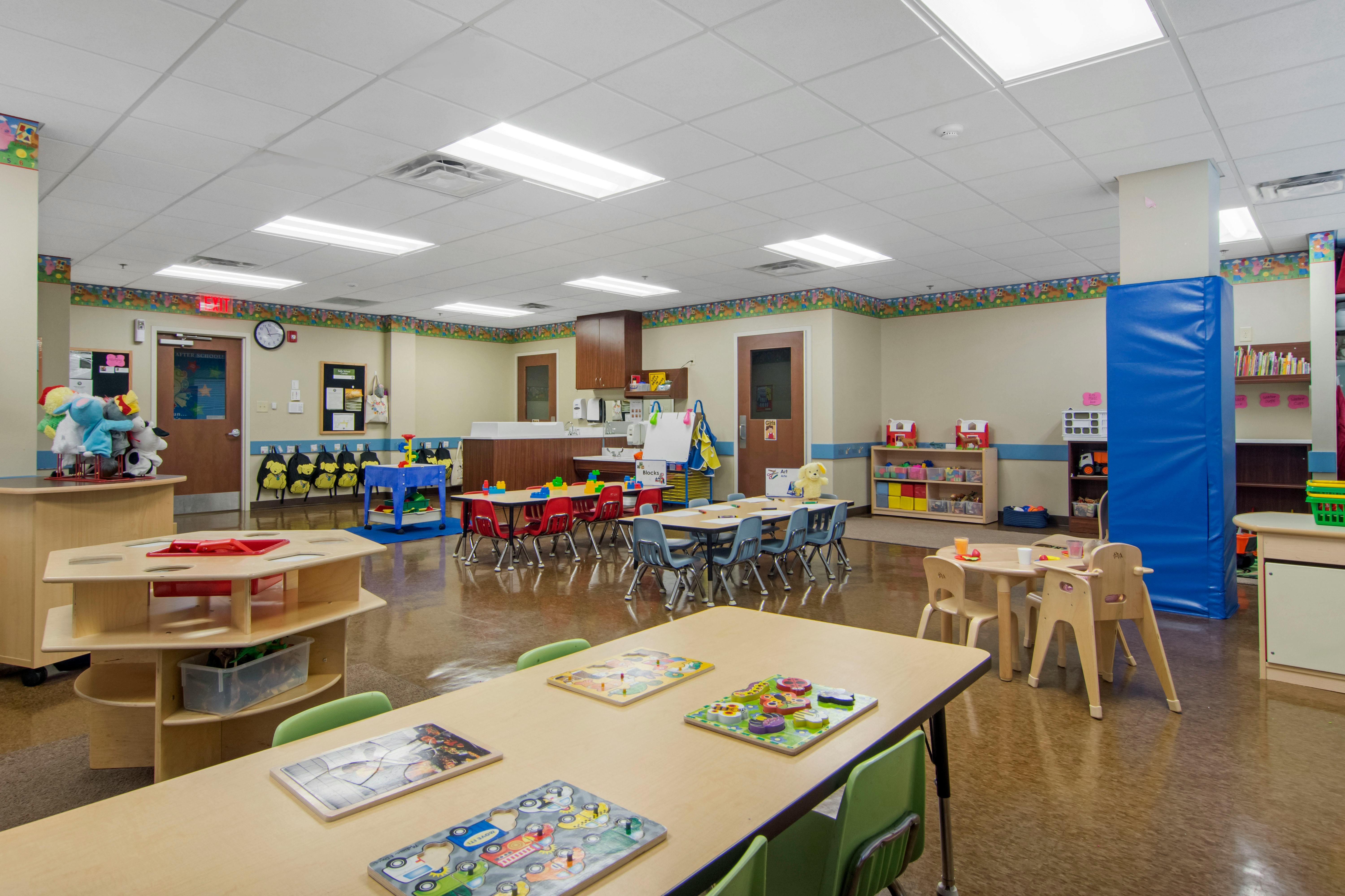 An empty early childhood classroom with small tables and chairs