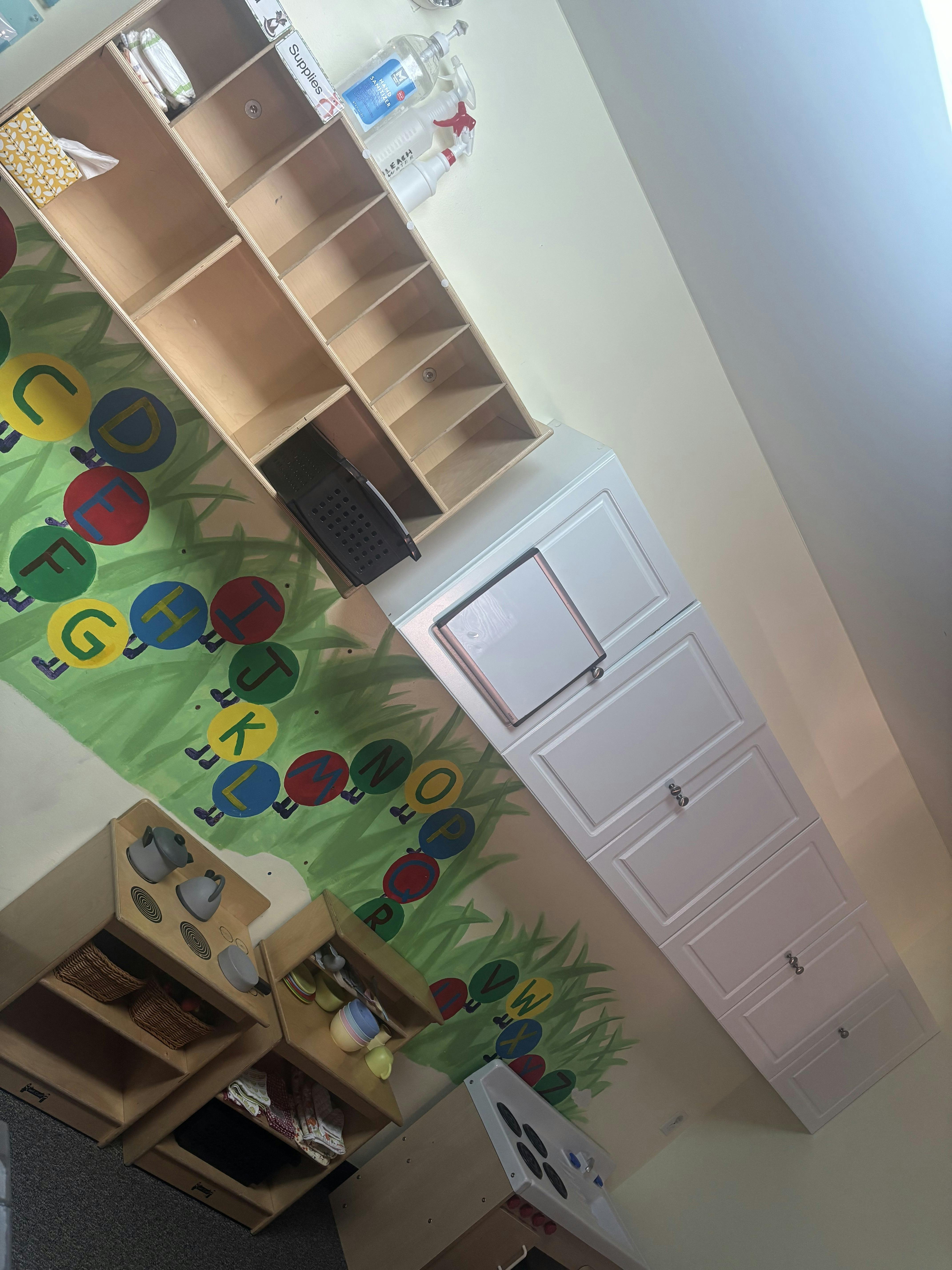 Classroom wall with alphabet mural and wooden play kitchens