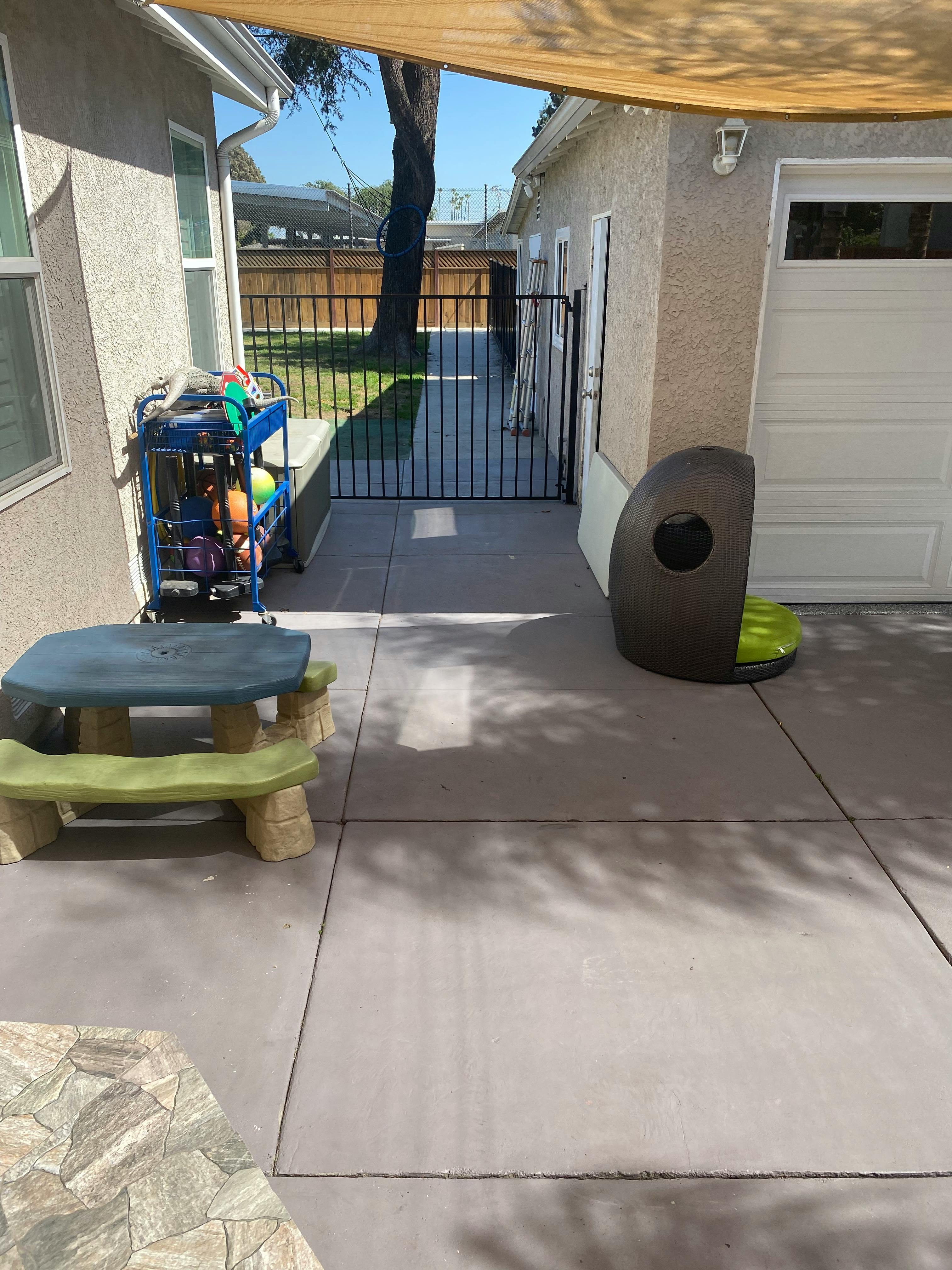 Patio with a small picnic table, blue cart, and pet bed