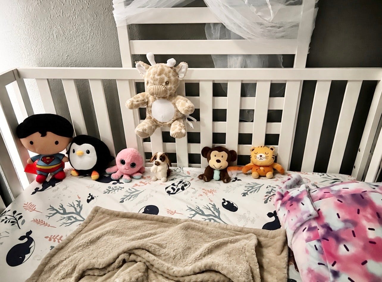 Collection of stuffed animals arranged in a white crib