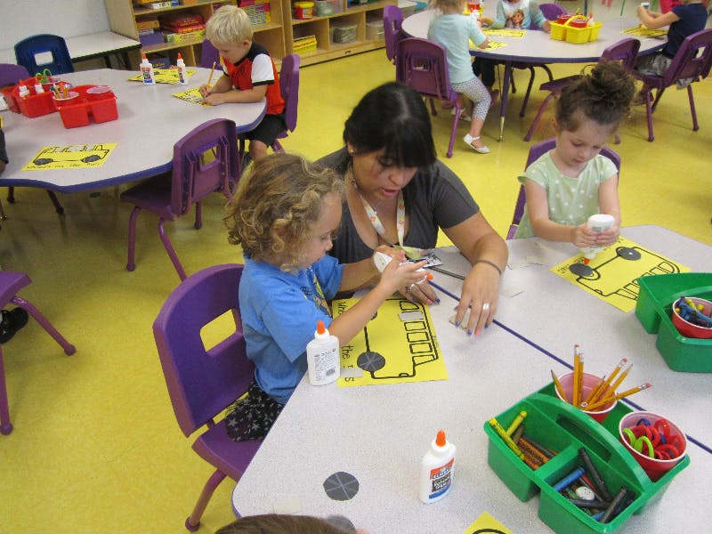 Adult and child doing crafts at a table in a classroom