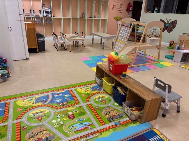 Child's playroom with small tables, chairs, a climbing structure, and playmats