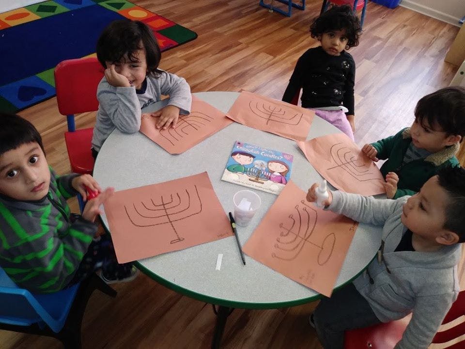 Children sitting around a table with menorah drawings