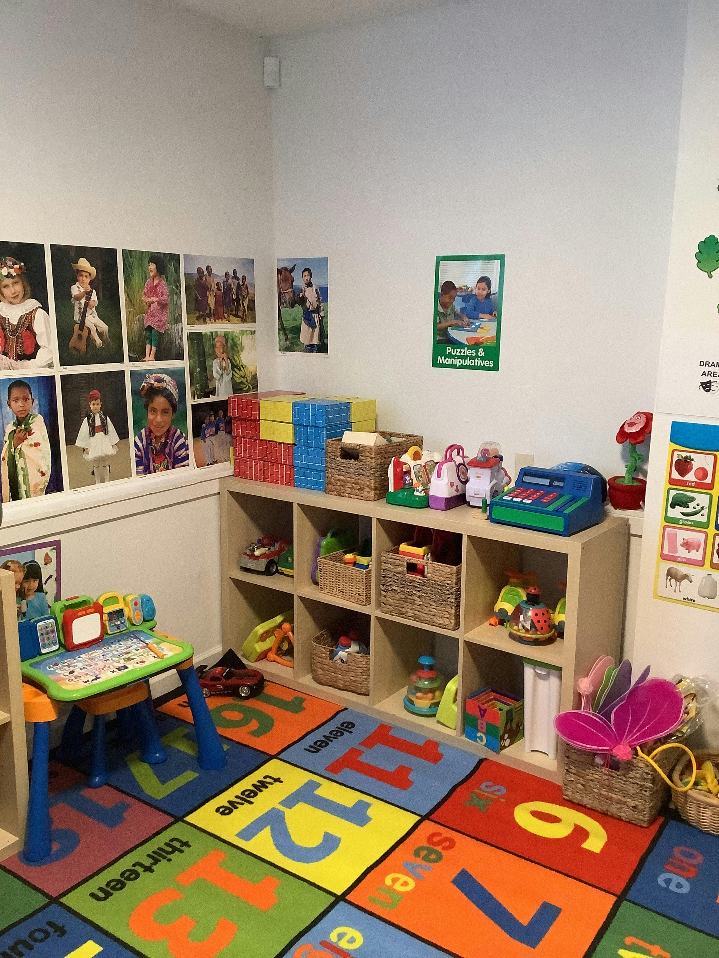 Playroom with a colorful number rug, toy shelves, and pictures on the wall