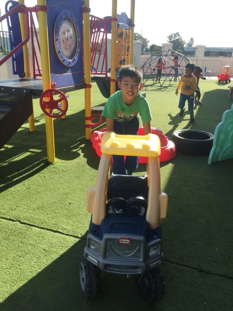Child standing behind a toy truck on a playground