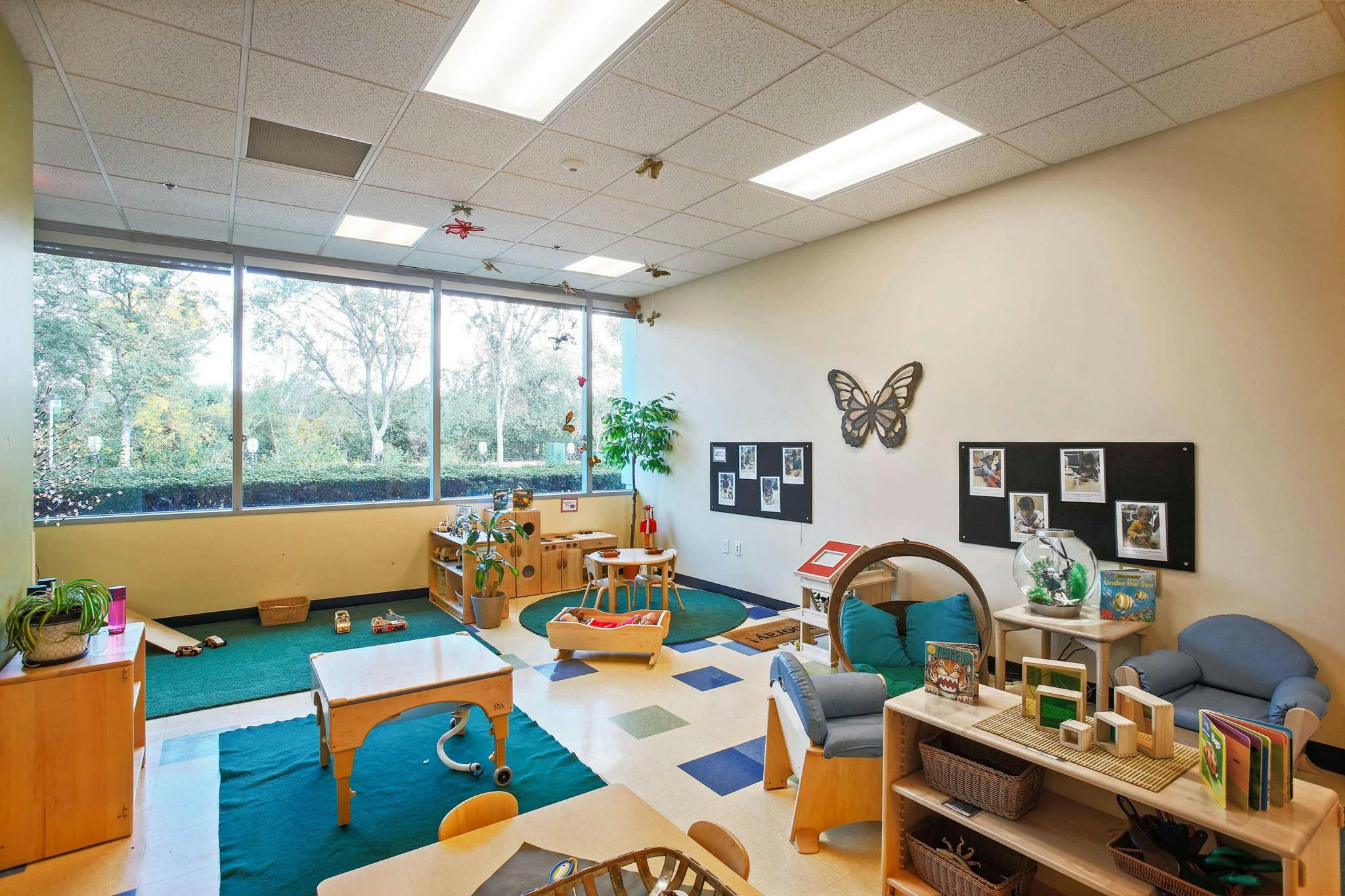 Classroom with large windows, small tables, chairs, and play areas