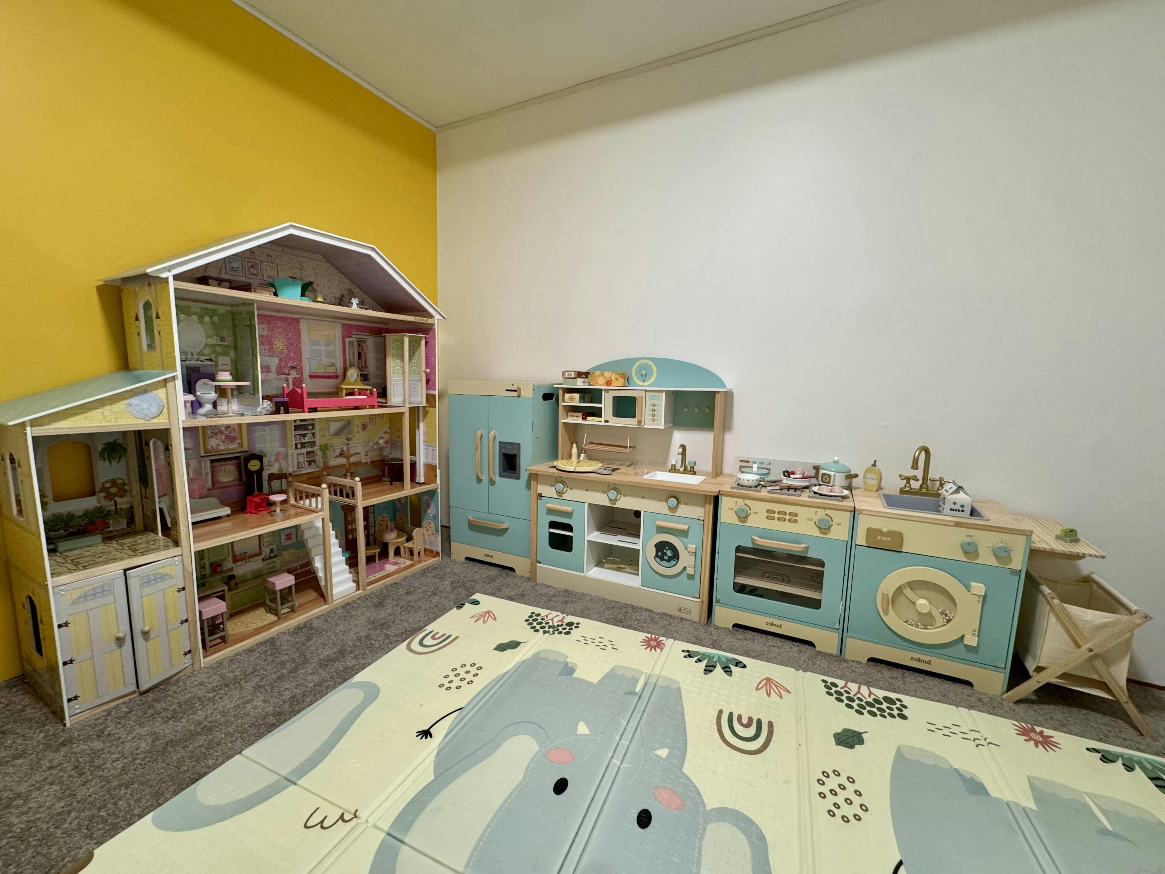 Dollhouse and play kitchen set in a room