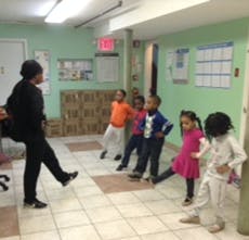 Person leading a group of children in an indoor exercise
