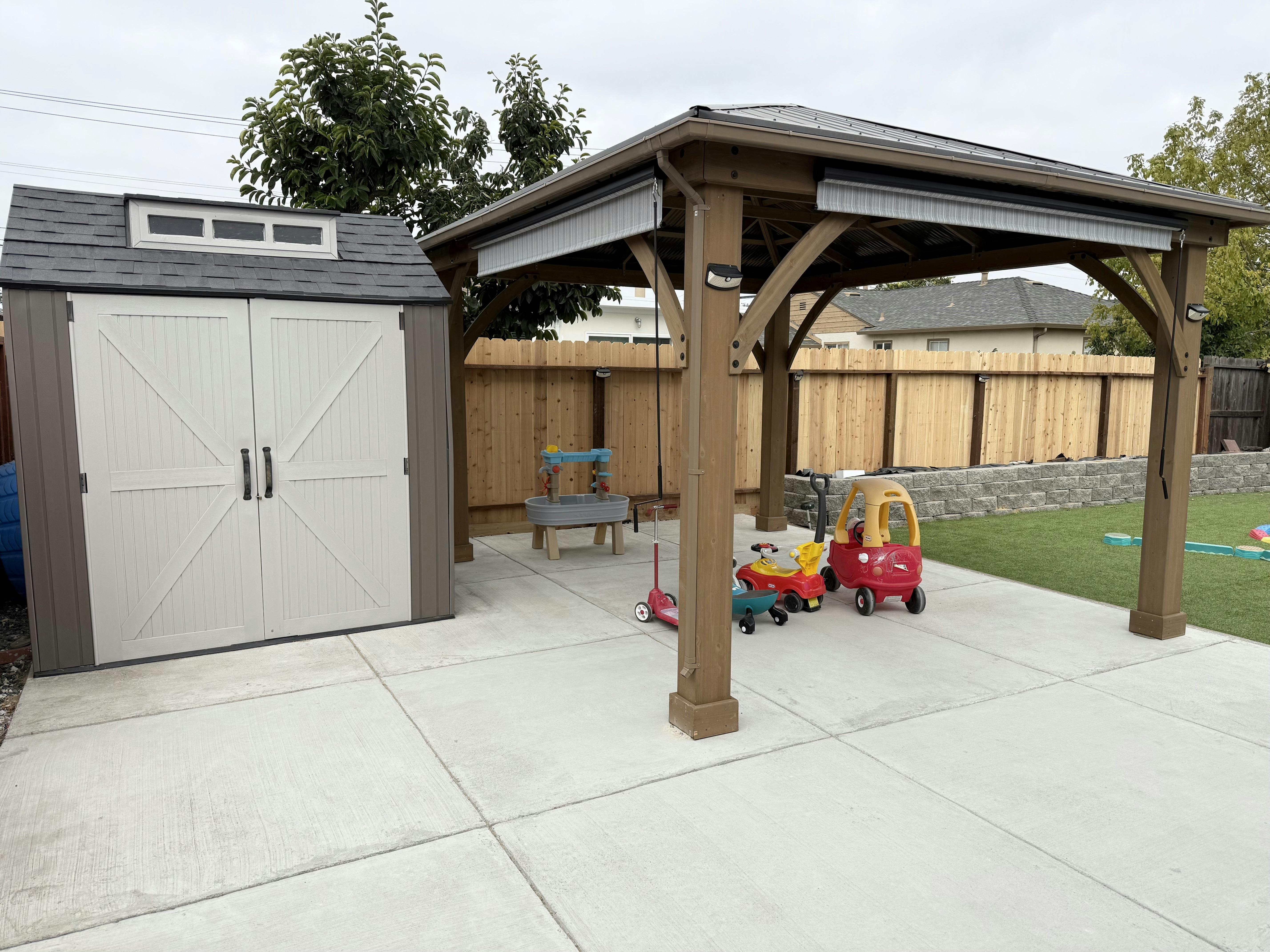 Outdoor shed and wooden gazebo with children's toys on a patio
