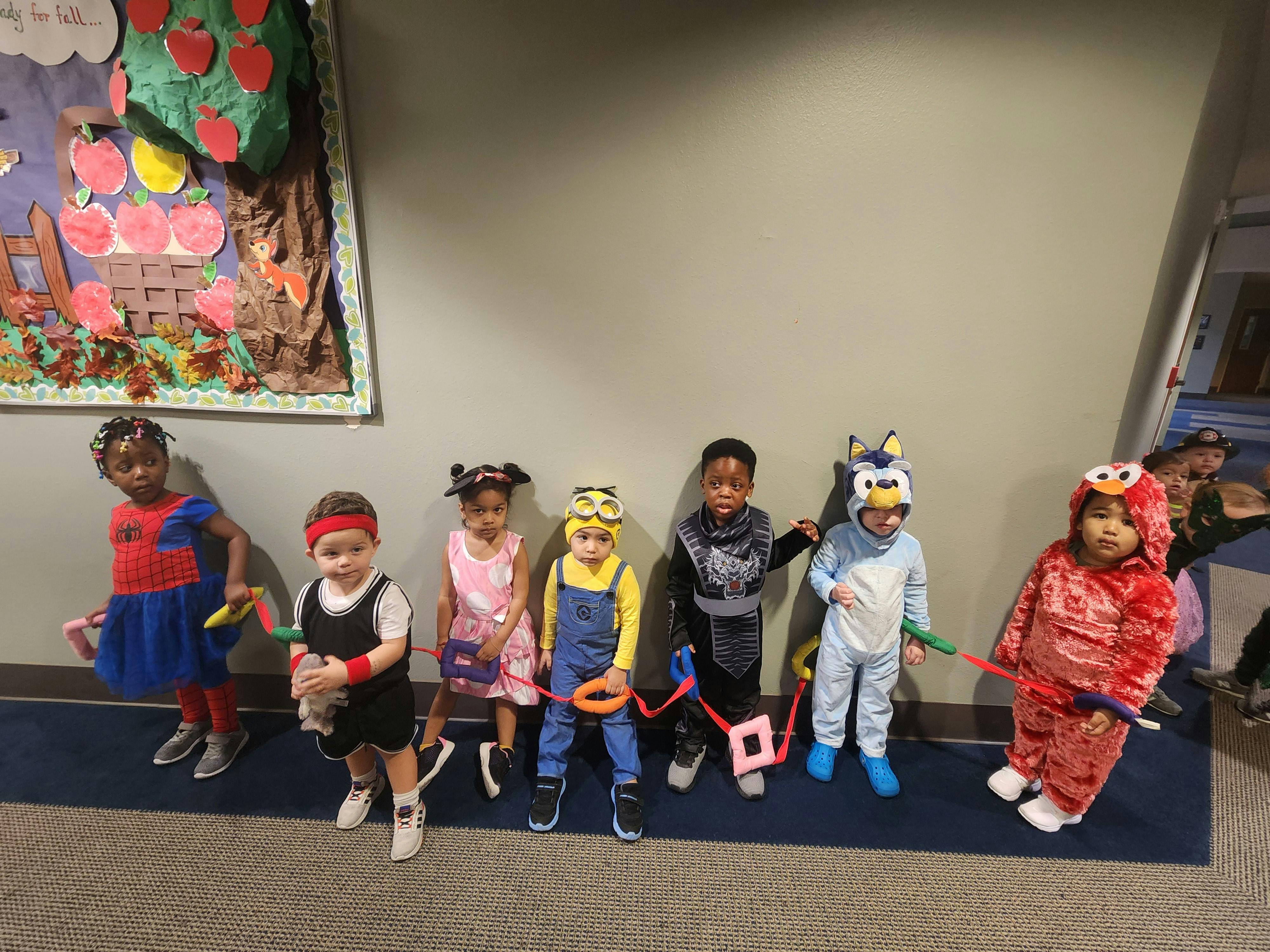 Children in costumes holding hands with balloon animals