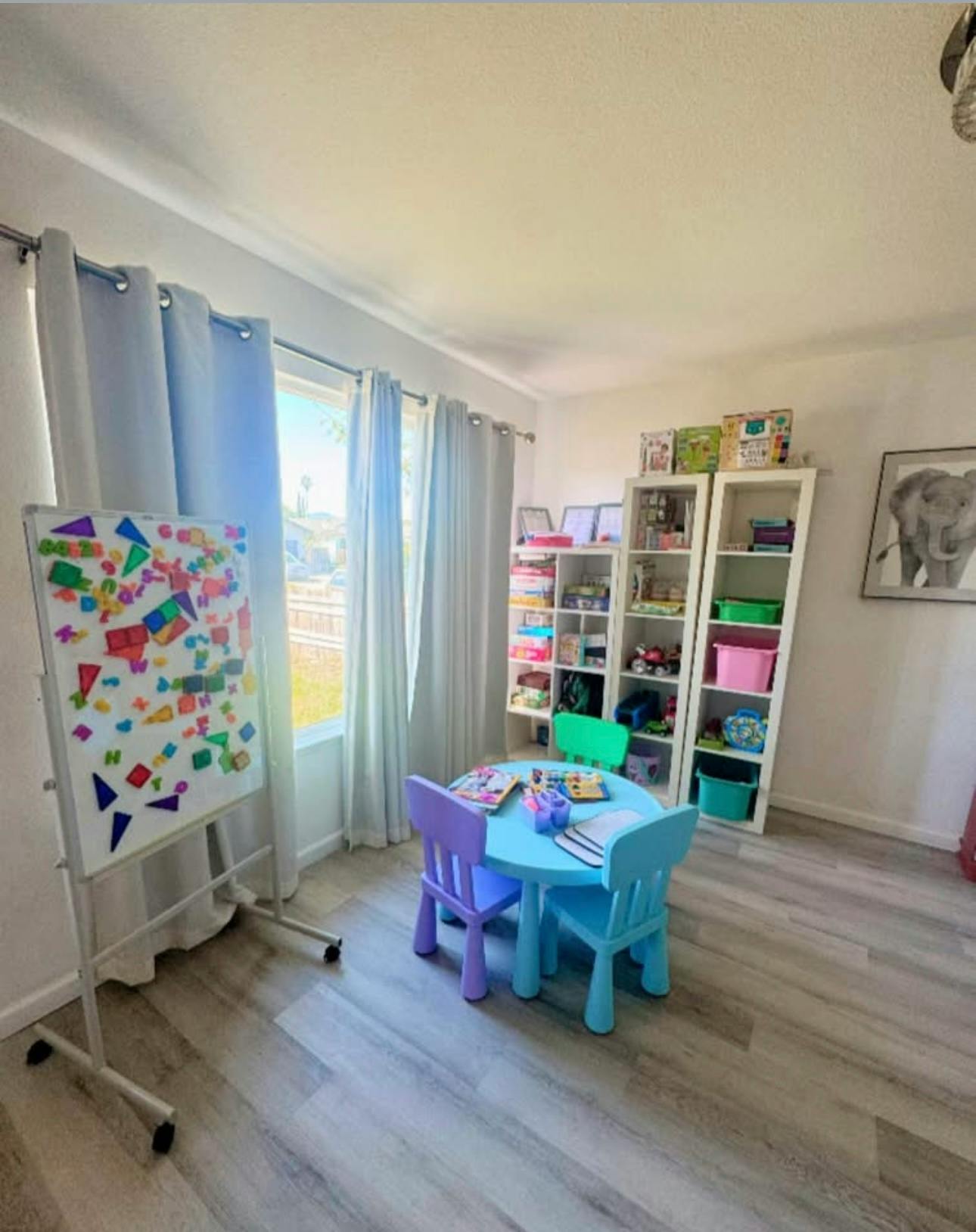 Playroom with a whiteboard, a small table with chairs, and bookshelves