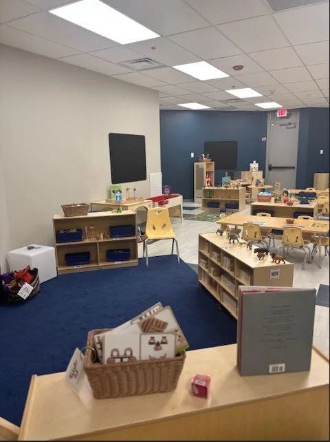 Classroom with tables, chairs, and shelves with toys and books