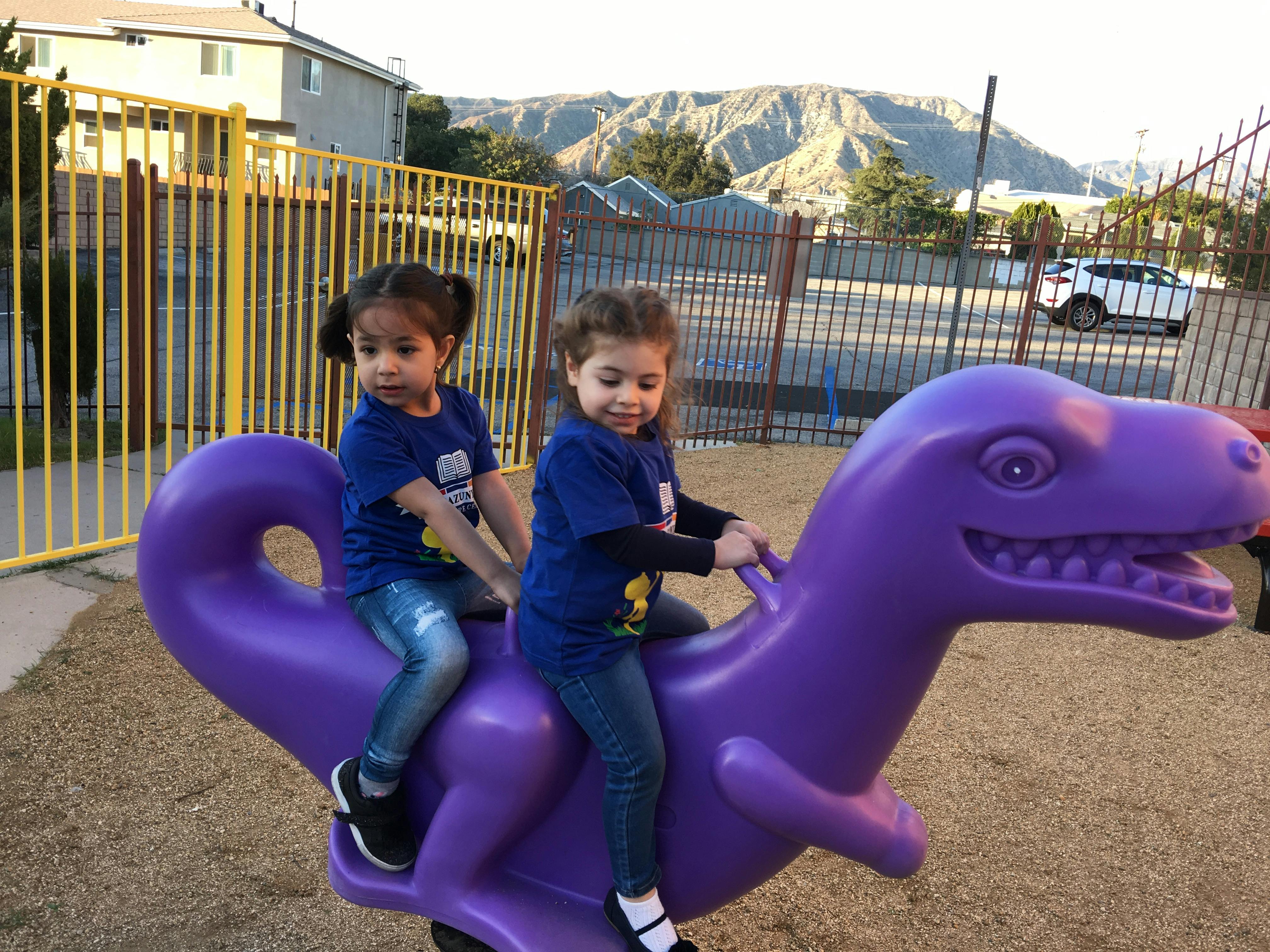 Two children on a purple dinosaur spring rider