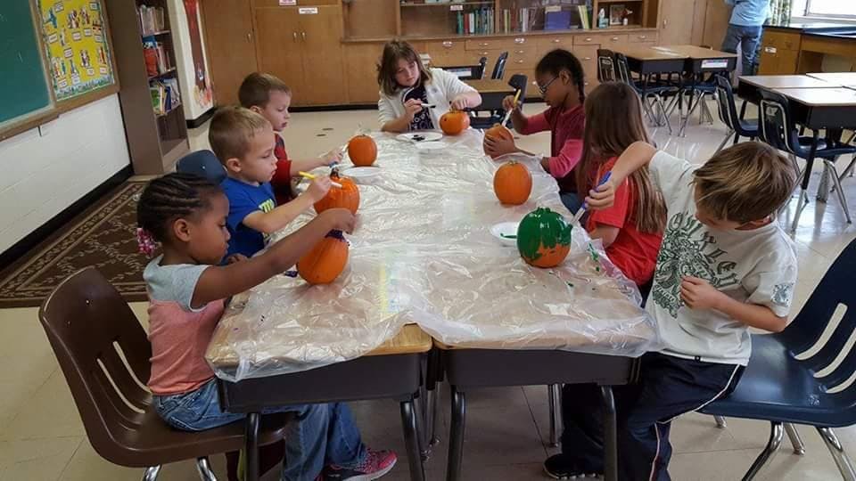 Children painting pumpkins in a classroom
