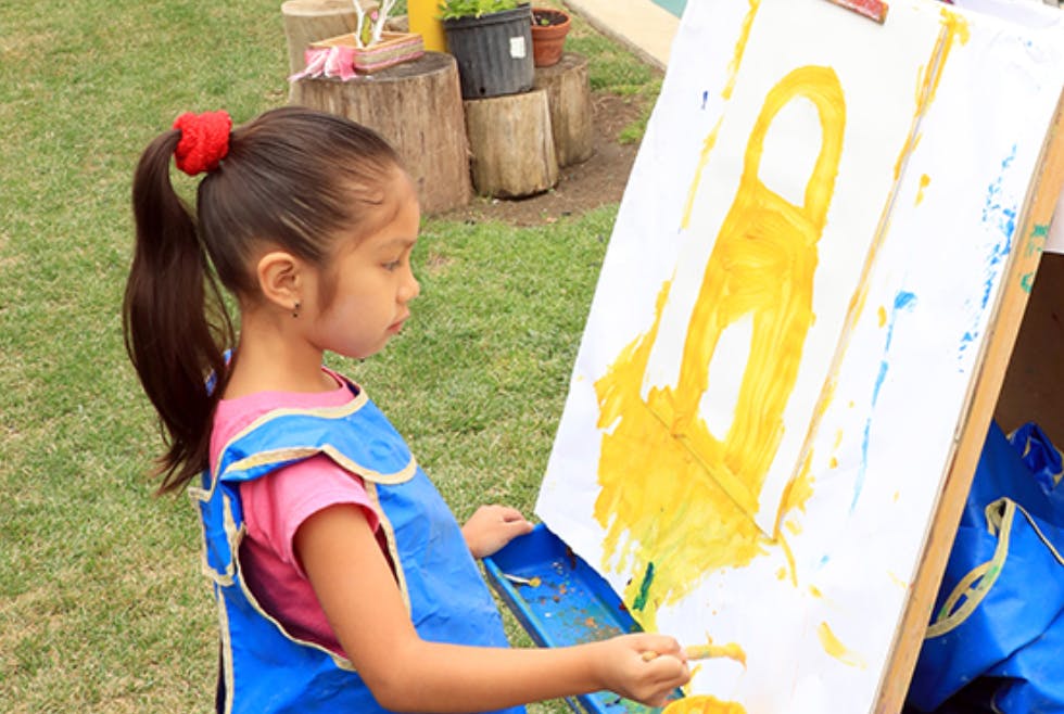 Child painting on an easel outdoors