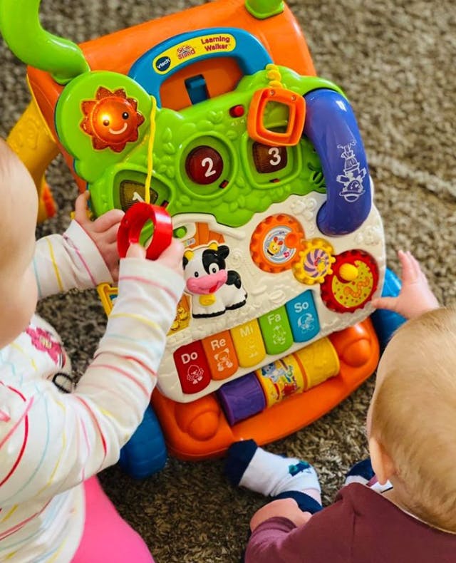 Two children playing with a colorful activity toy