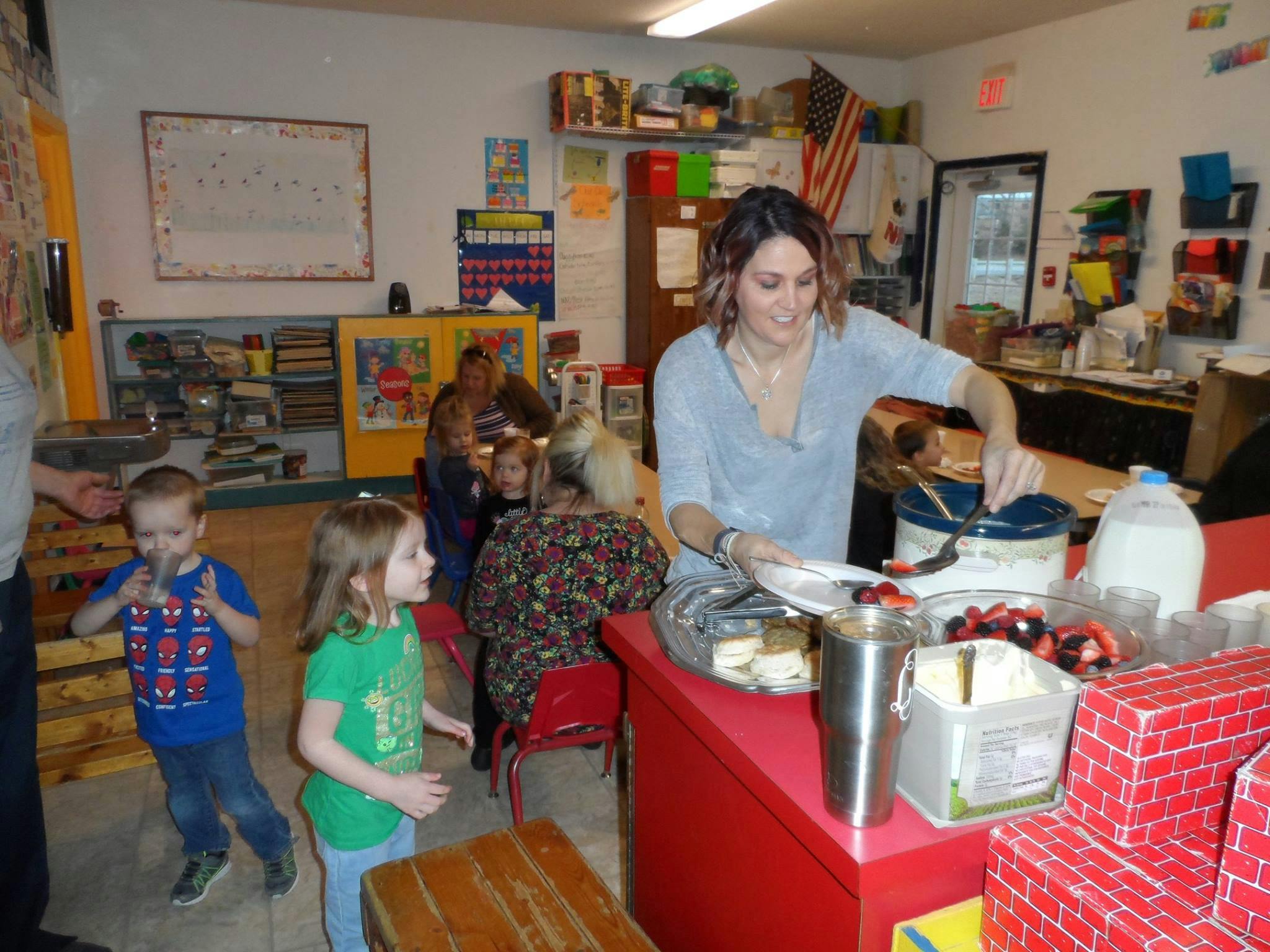 Person serving food to children in a classroom