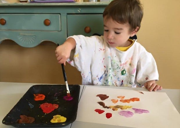 Child painting on paper with a brush