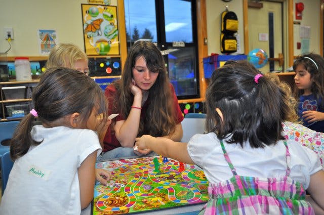 Adult and children playing a board game in a classroom