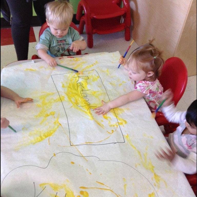 Children drawing on a large sheet of paper with crayons