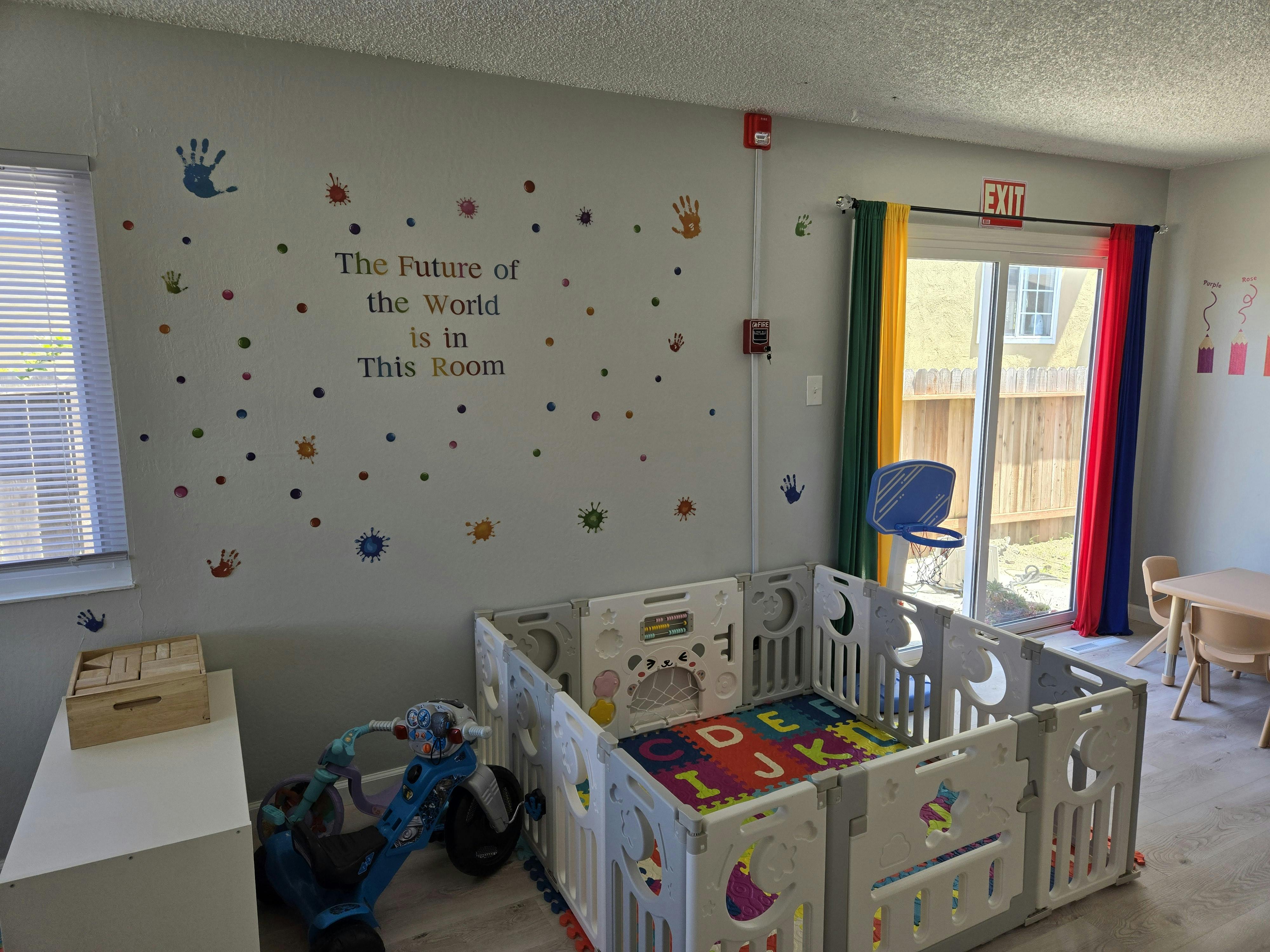 Playpen with alphabet mat in a room with wall decals and sliding door