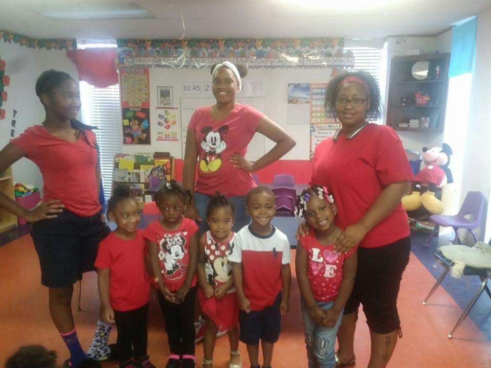 Three adults and multiple children posing in a classroom