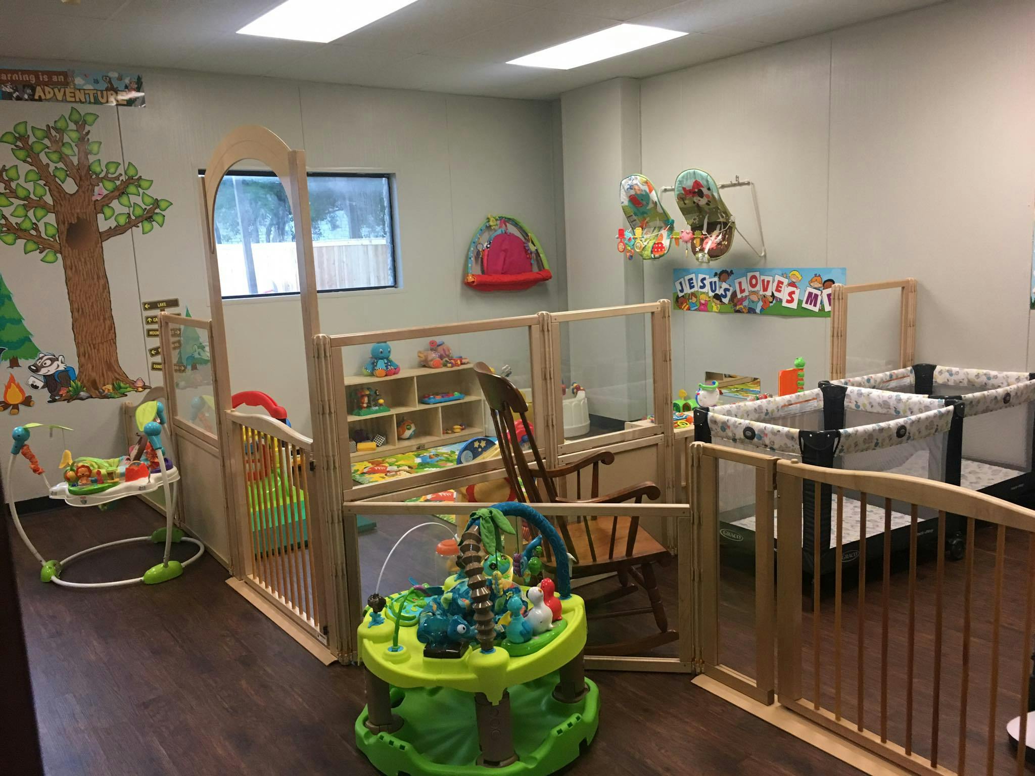 Infant room with playpens, cribs, and play areas