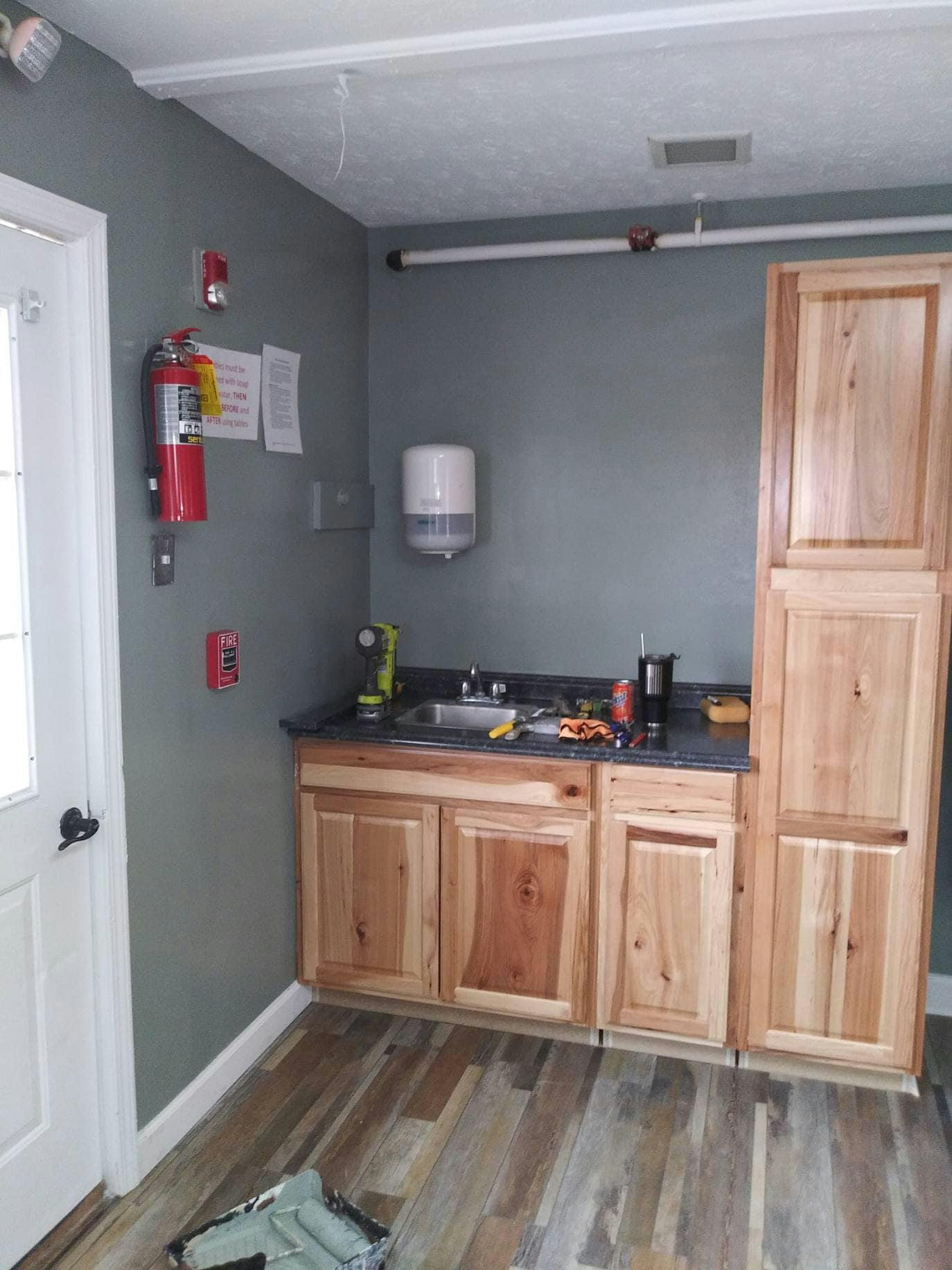 newly installed wooden cabinets and sink in a room with grey walls