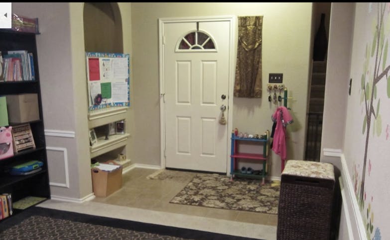 Entryway with a white door, rug, and storage shelves