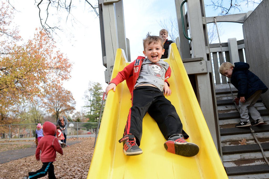 Child sliding down a yellow slide on a playground