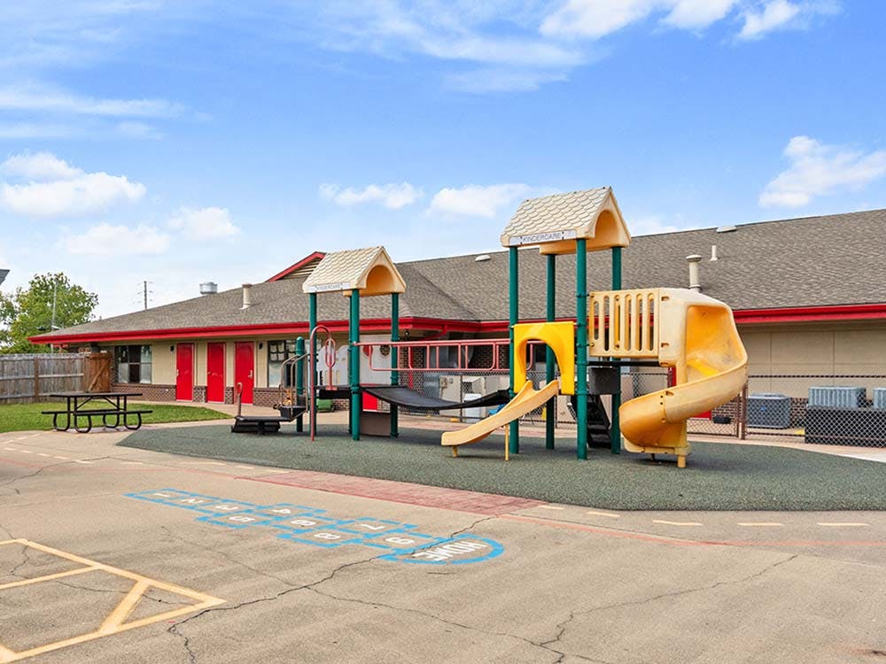 Playground with yellow and green equipment and a hopscotch court
