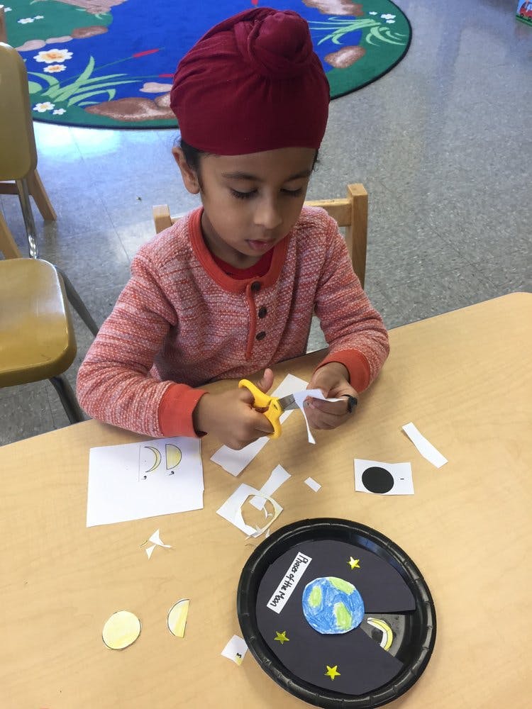 Child cutting paper with scissors at a table