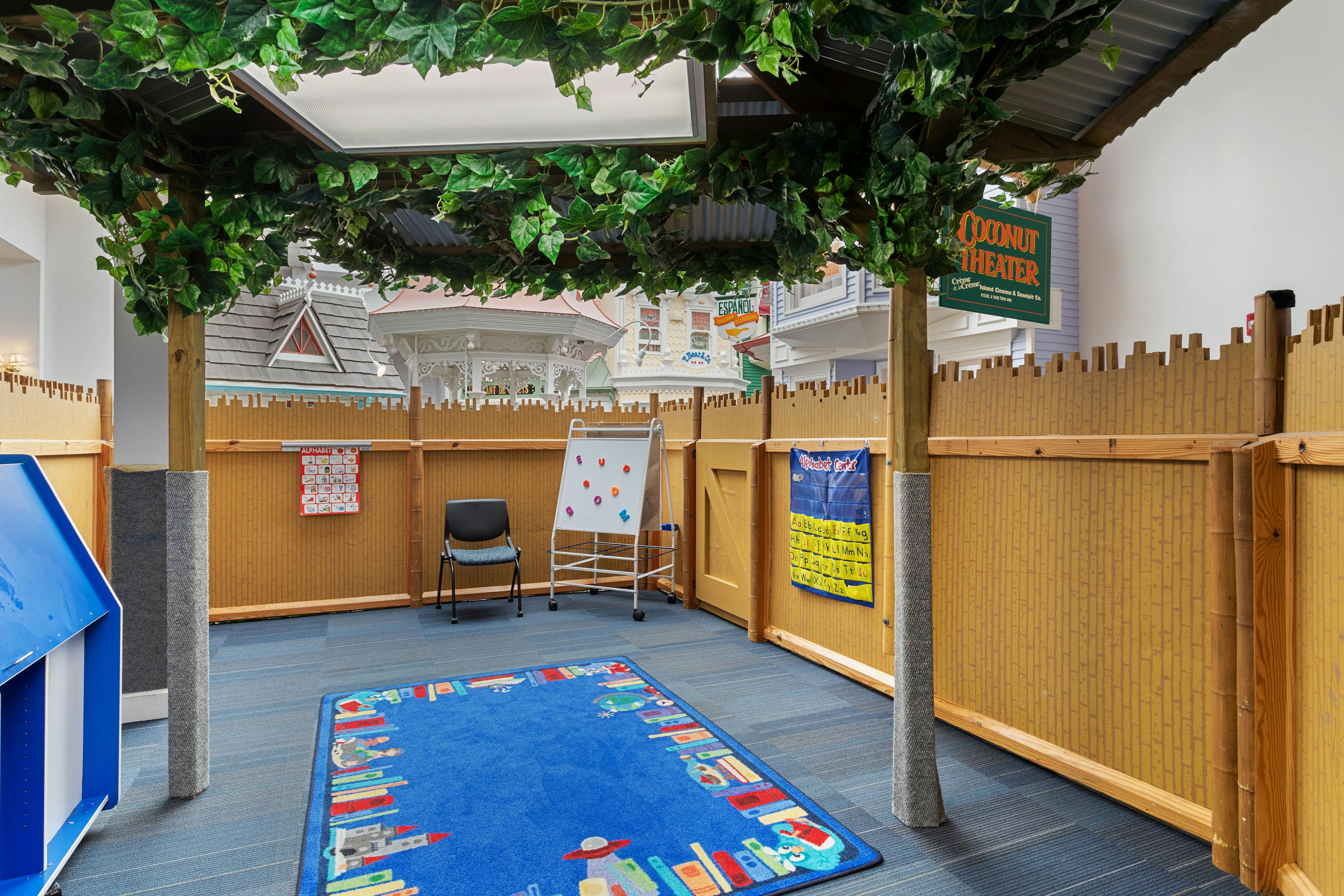 Children's play area with a blue rug, whiteboard, and bamboo-style walls