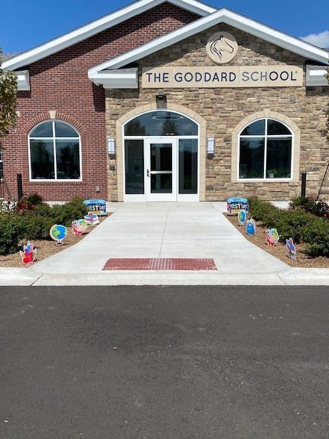 The Goddard School building entrance with a walkway and decorative signs