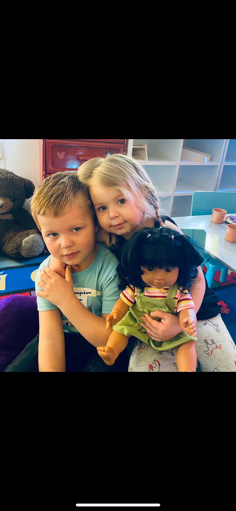 Child with arm around another child holding a doll