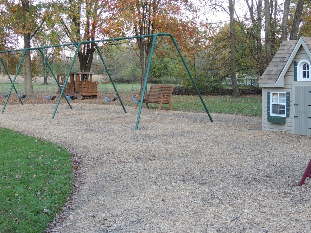 Swing set and playhouse on a wood chip playground