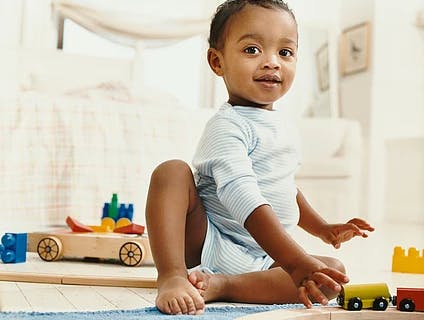 Child sitting on floor playing with wooden toy train